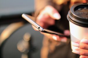Person holding coffee and cell phone 
