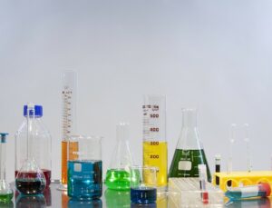 Multiple glass measuring instruments on a table with different colored liquids in them 
