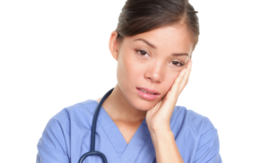 woman in scrubs looking stressed and sad