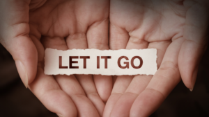 Hands holding a piece of paper that says let it go. 
